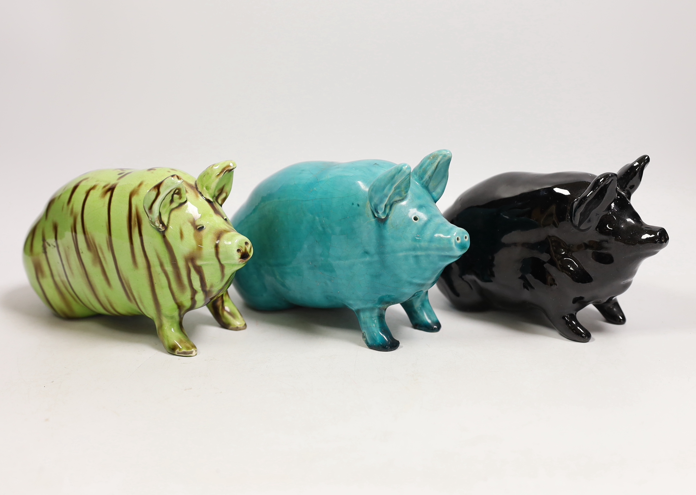 Three Wemyss style pigs in turquoise, pale green / brown and black glazes, one indistinctly marked W.. 15cm